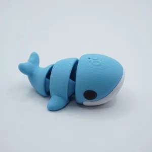 Ballena articulada impresa en 3D en PLA+ azul con vientre blanco, cuerpo segmentado y cola móvil